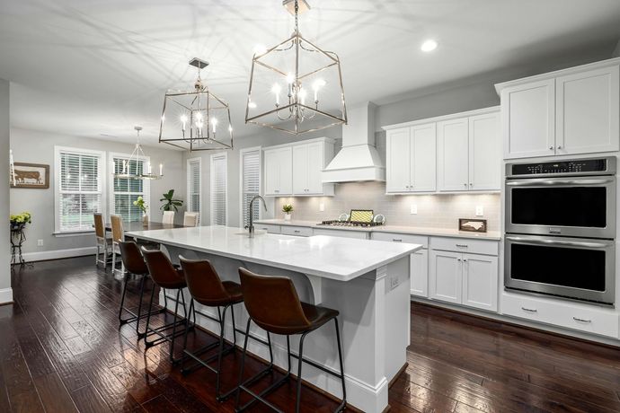 A kitchen with white cabinets and stainless steel appliances and a large island.