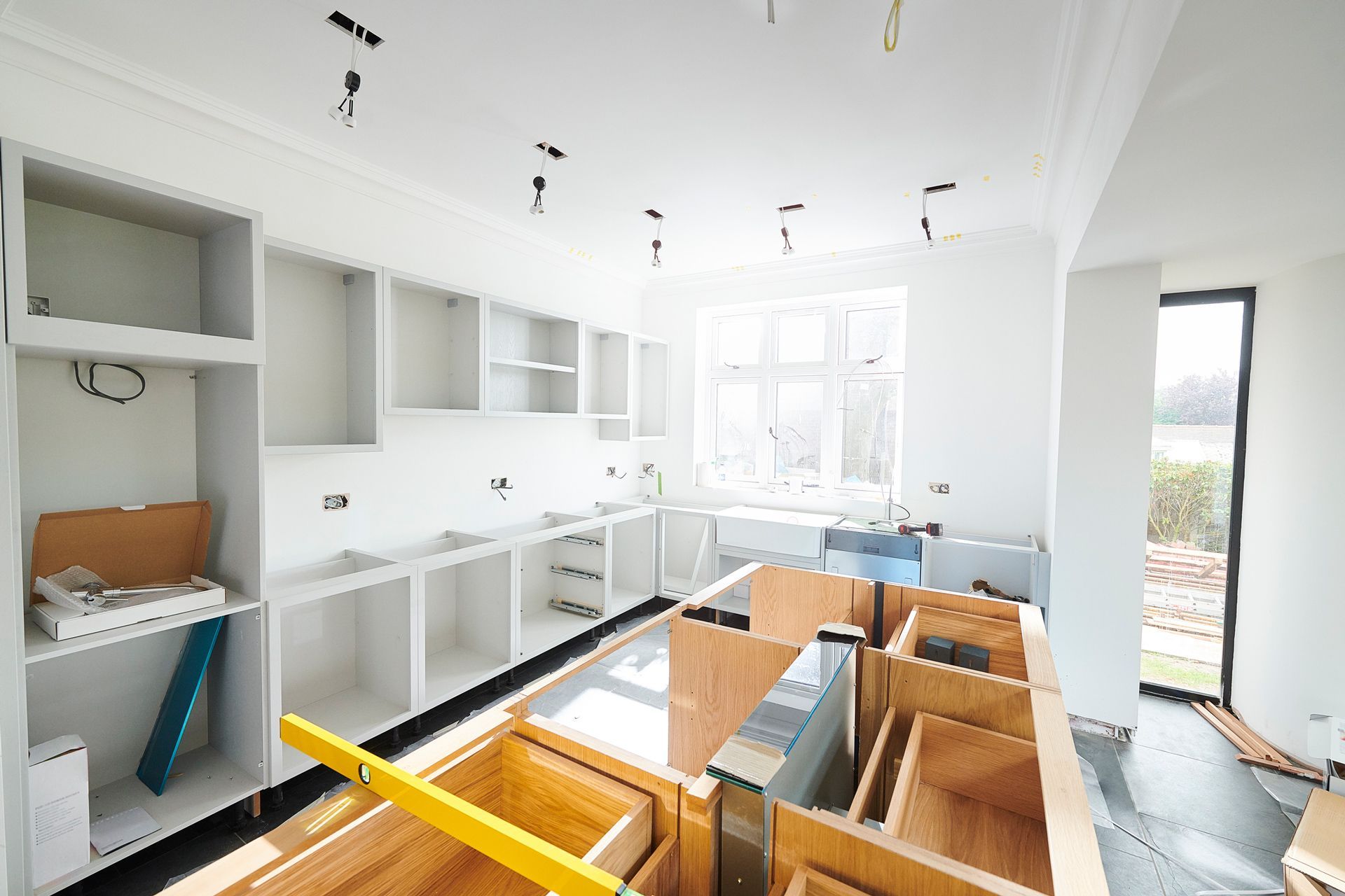 A kitchen under construction with wooden cabinets and a yellow level.