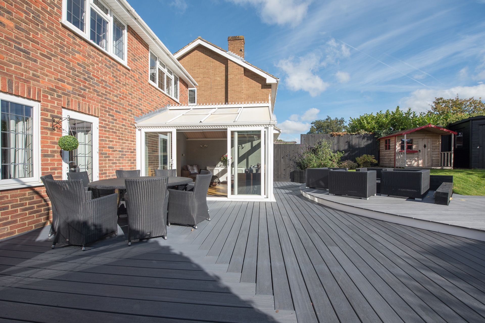 A large patio with a table and chairs in front of a brick house.