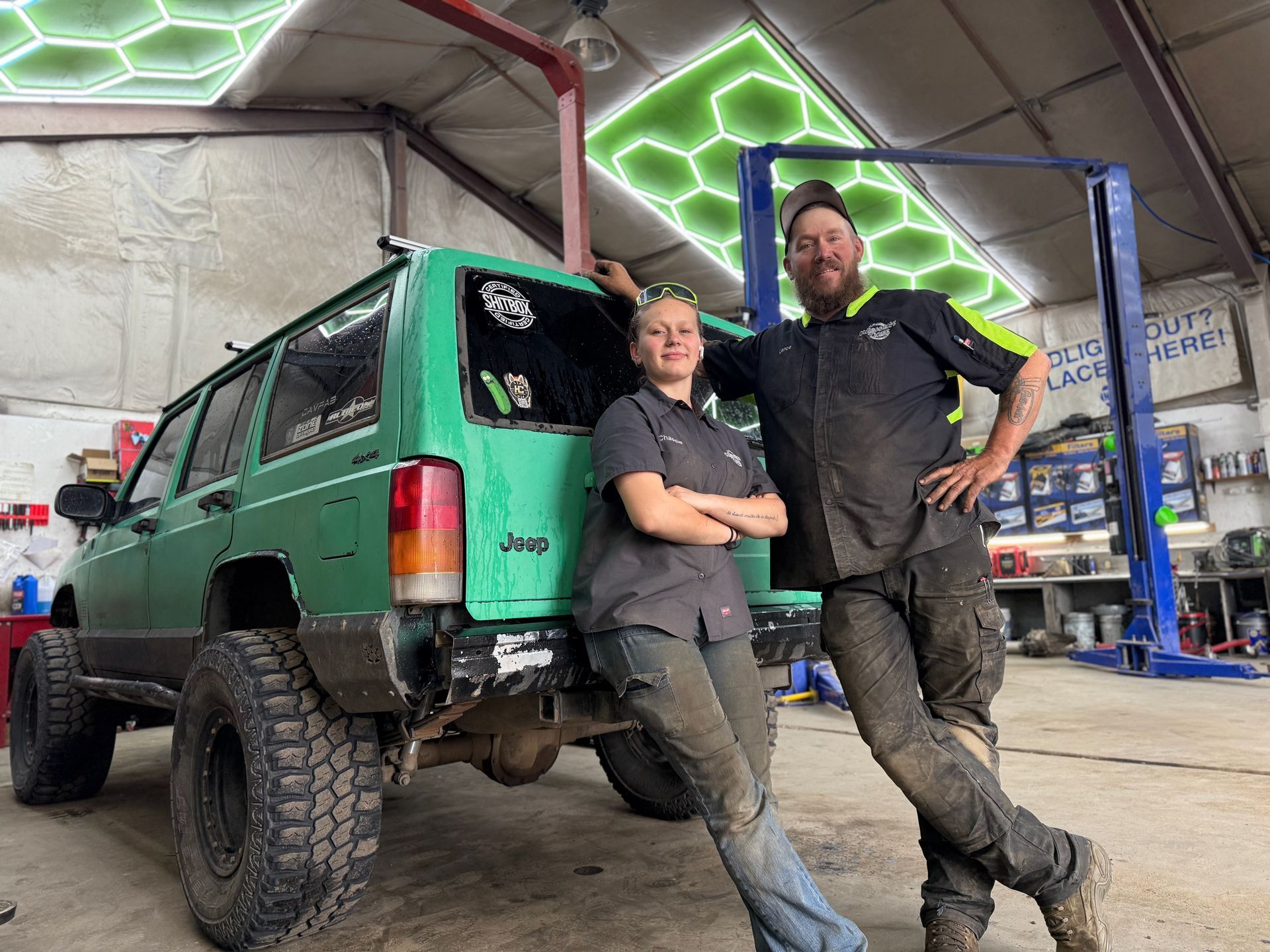 A group of people are posing for a picture in front of a truck in a garage.