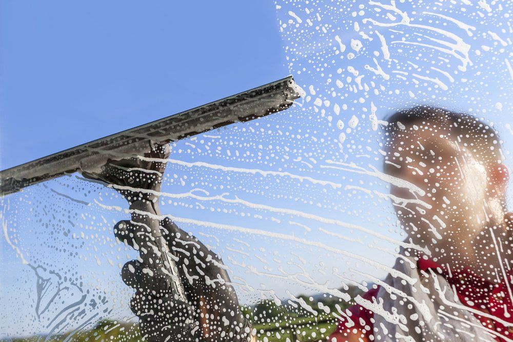 Man Wiping Off the Bubbles on the Glass — Highlands Window Cleaning in Mittagong, NSW