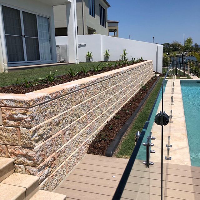 A large brick wall surrounds a swimming pool