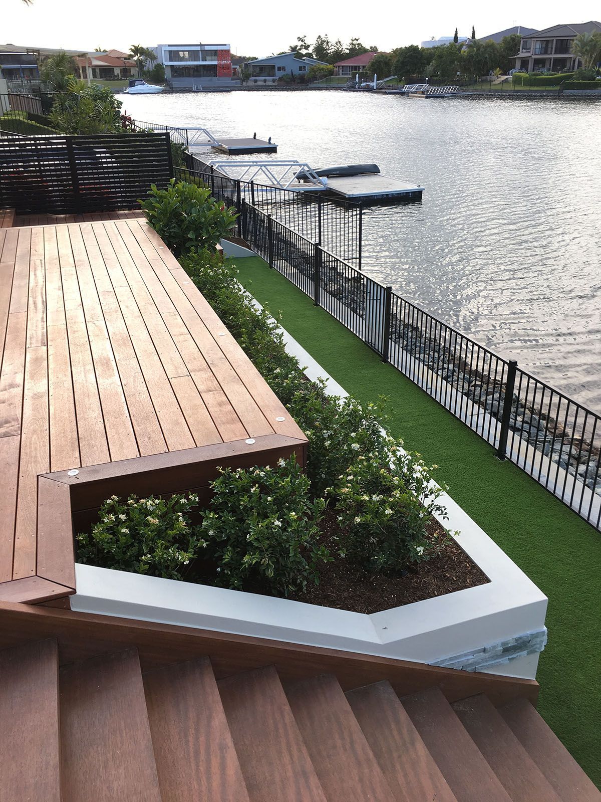 A wooden deck with stairs leading up to it overlooking a body of water.