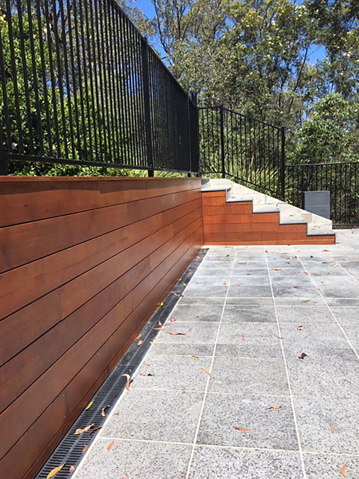 A wooden deck with stairs leading up to it and a metal railing.