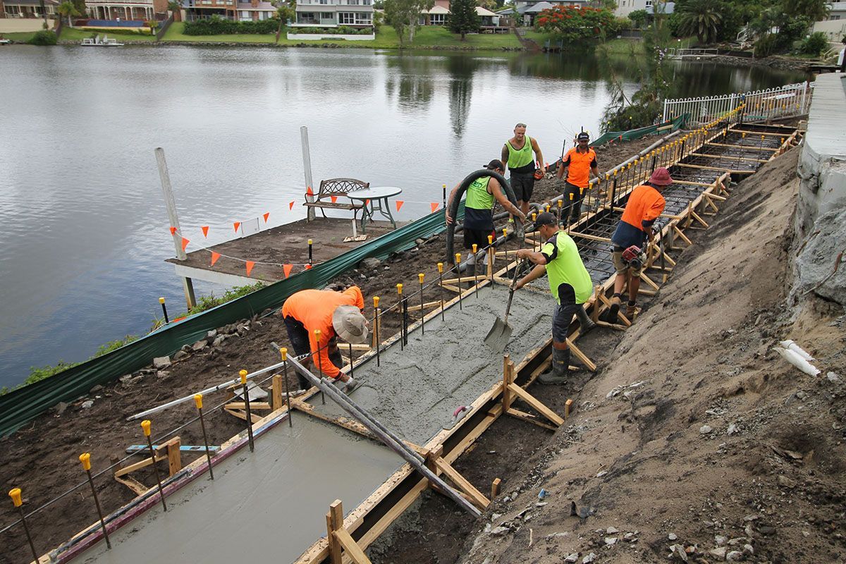 A group of people are working on a construction site next to a body of water.