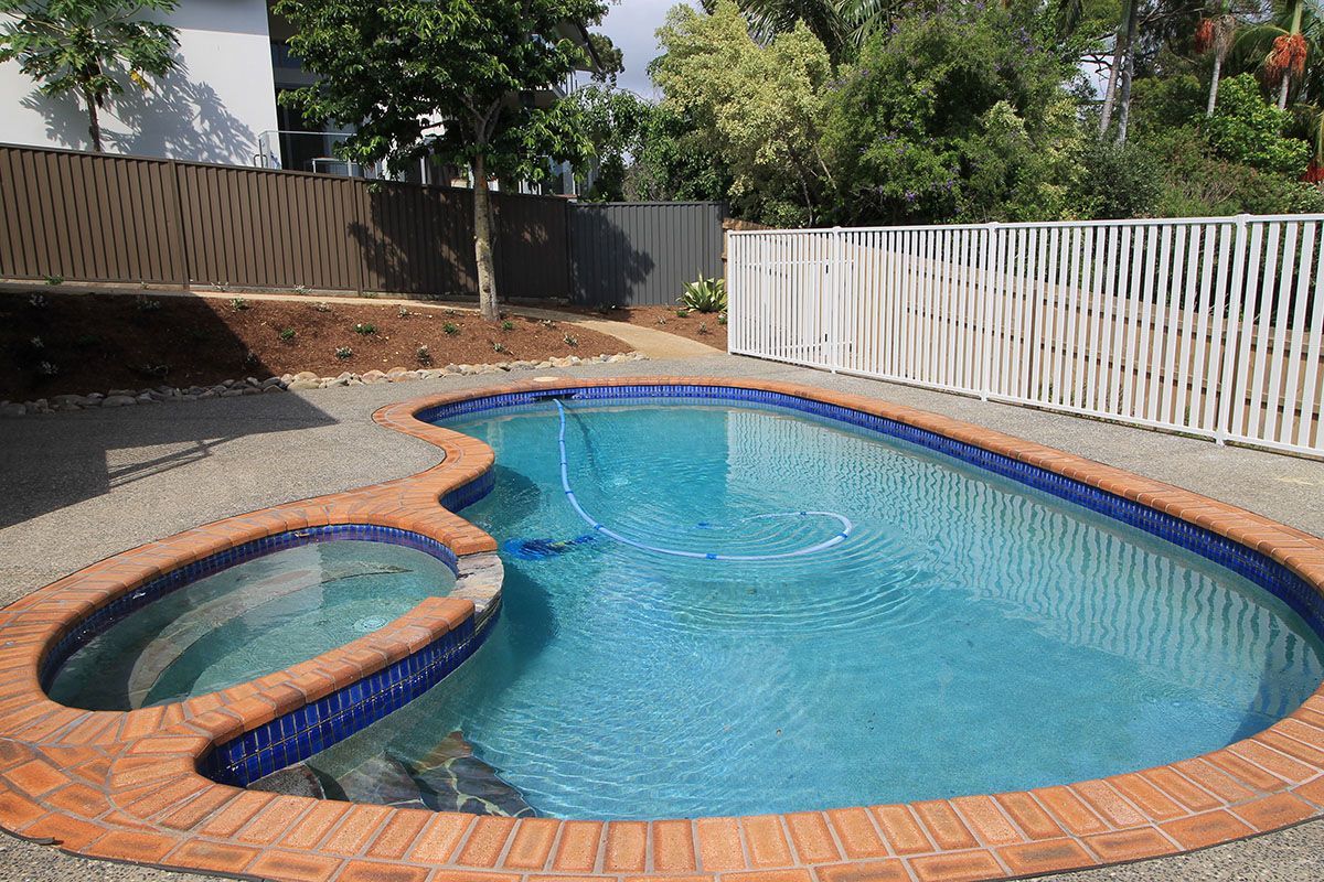 A large swimming pool with a white fence around it