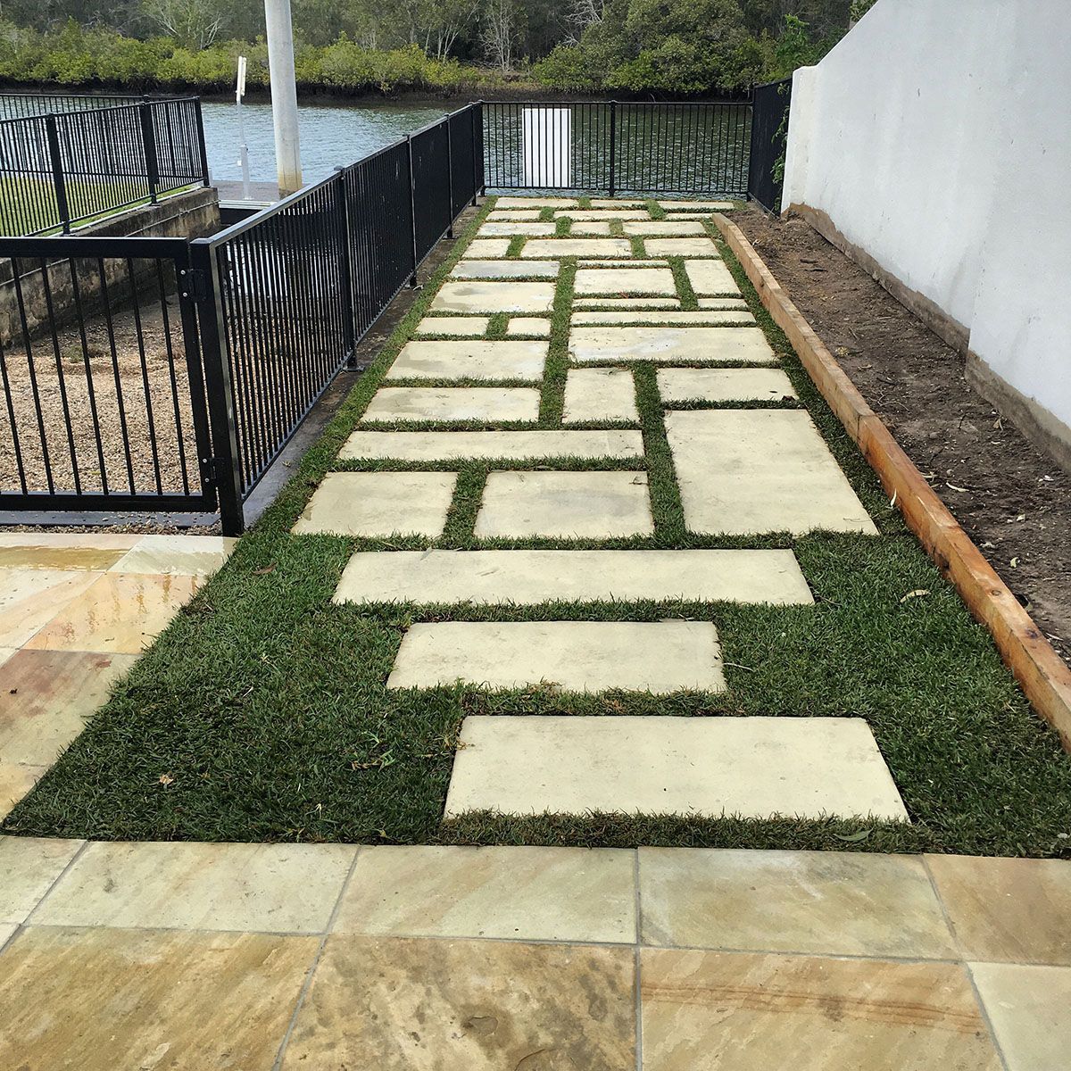 A stone walkway surrounded by grass and a fence