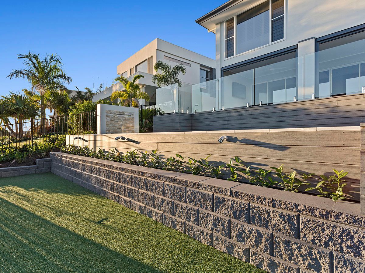 A large house with a brick wall and a glass fence surrounding it.