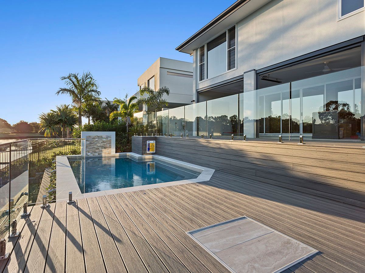 There is a large swimming pool in the backyard of a house.