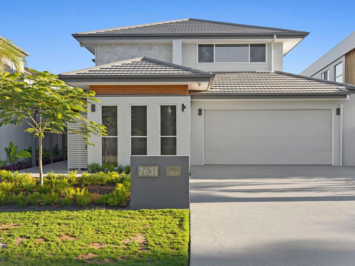 A white house with a gray roof and a white garage door