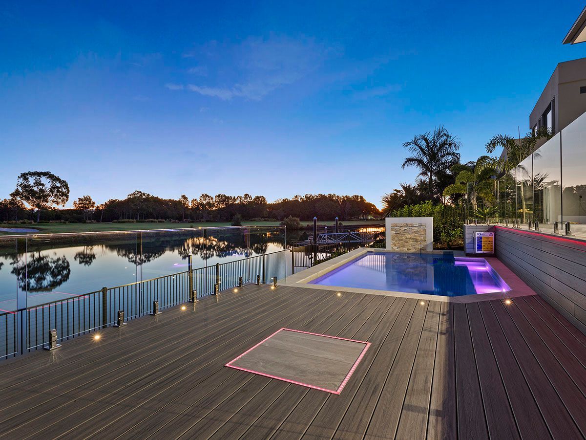 A large swimming pool is surrounded by a wooden deck