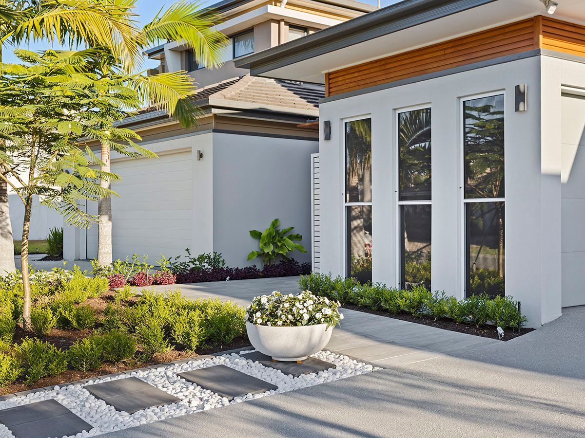A white house with a lot of windows and a potted plant in front of it.