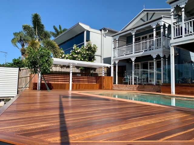 A large house with a swimming pool and a wooden deck in front of it.