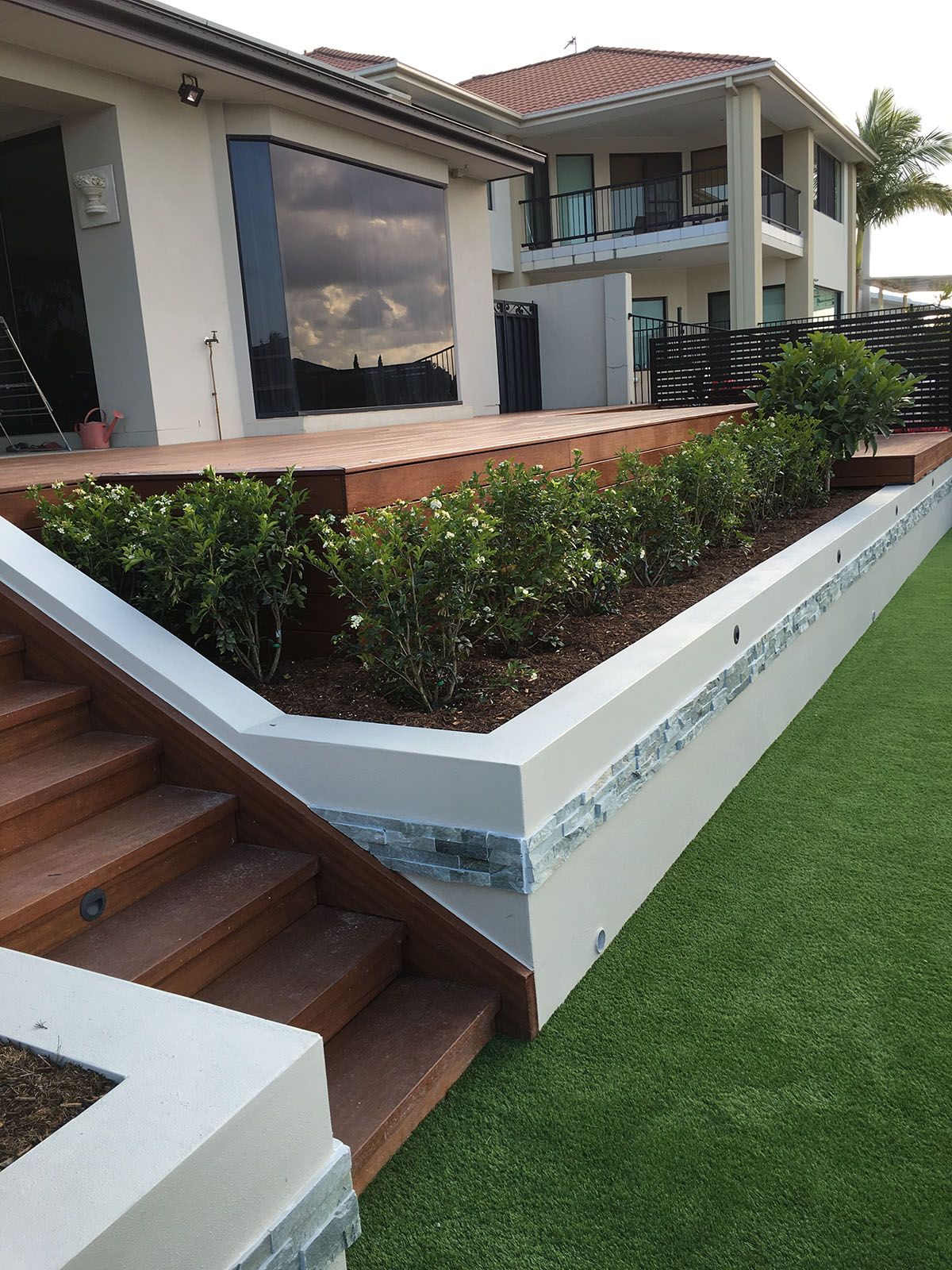 A house with stairs leading up to it and a lawn in front of it.