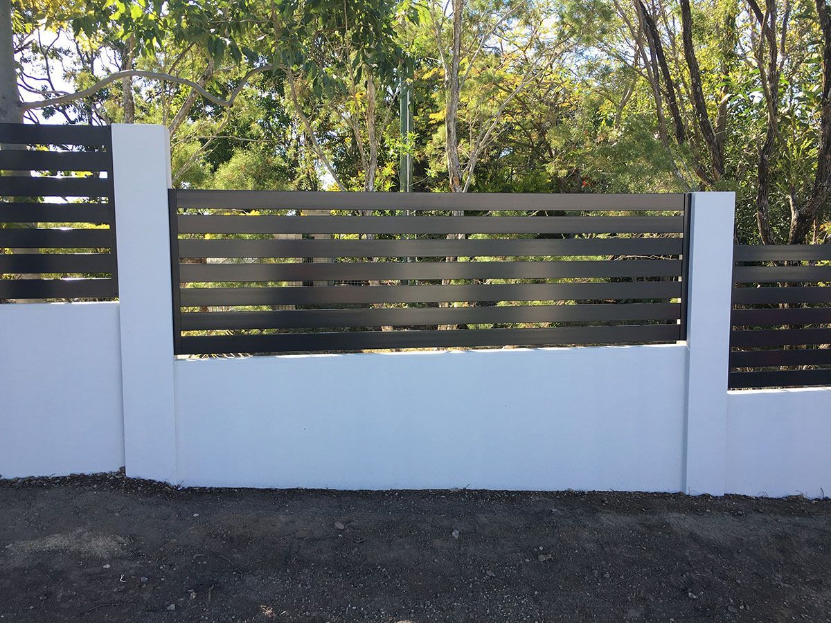 A white wall with a black fence surrounded by trees