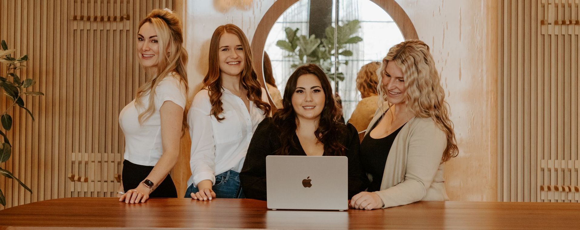 A group of women are sitting at a table with a laptop.