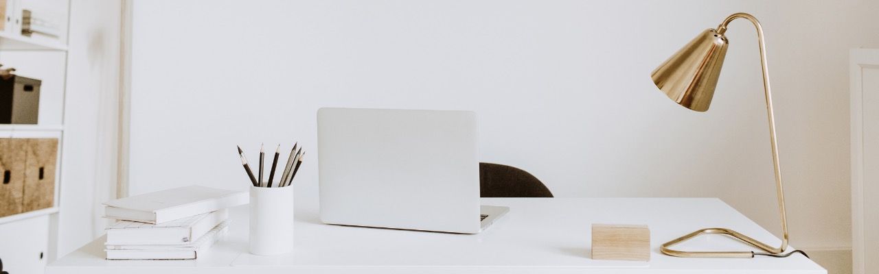 A white desk with a laptop on it