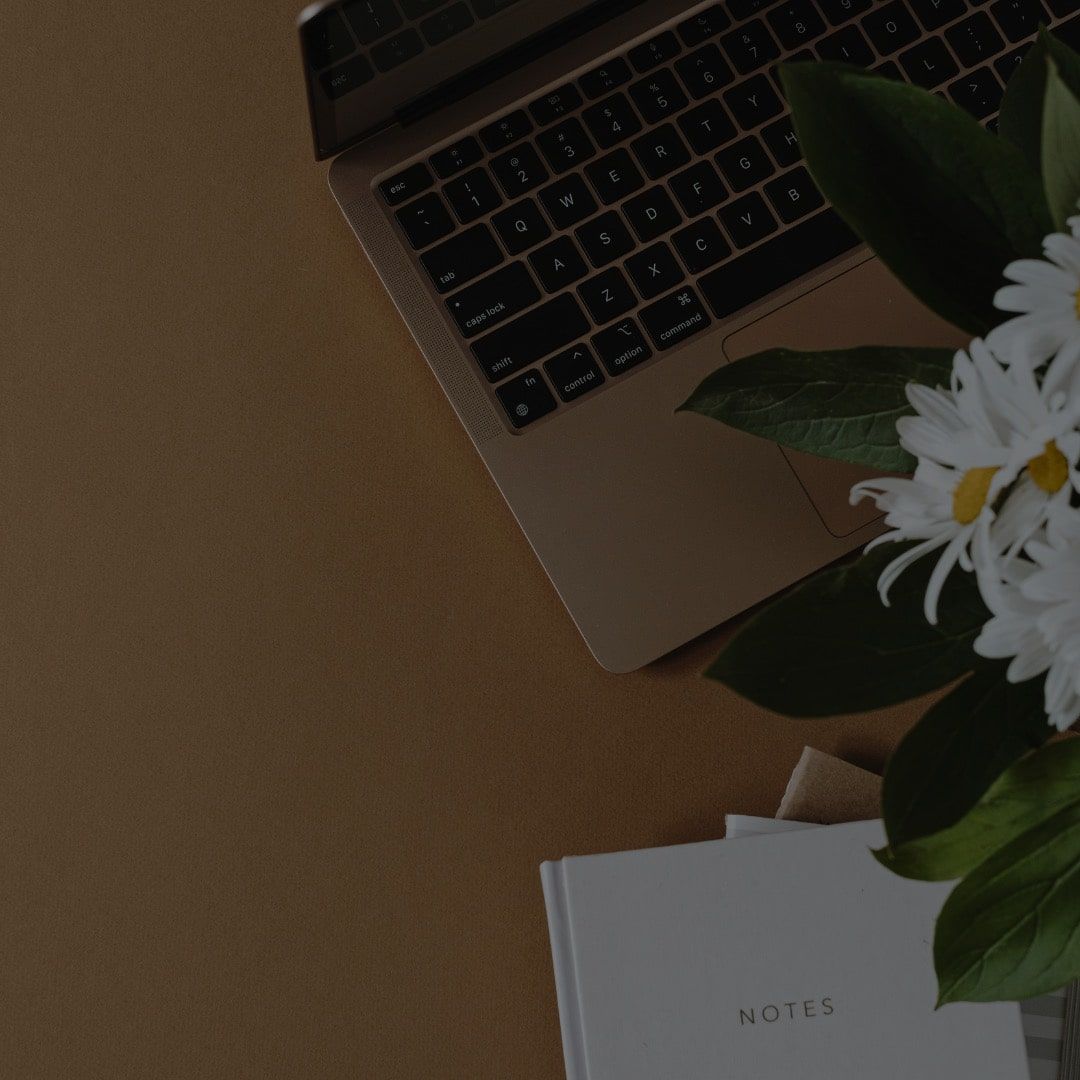 computer on desk with flowers beside it