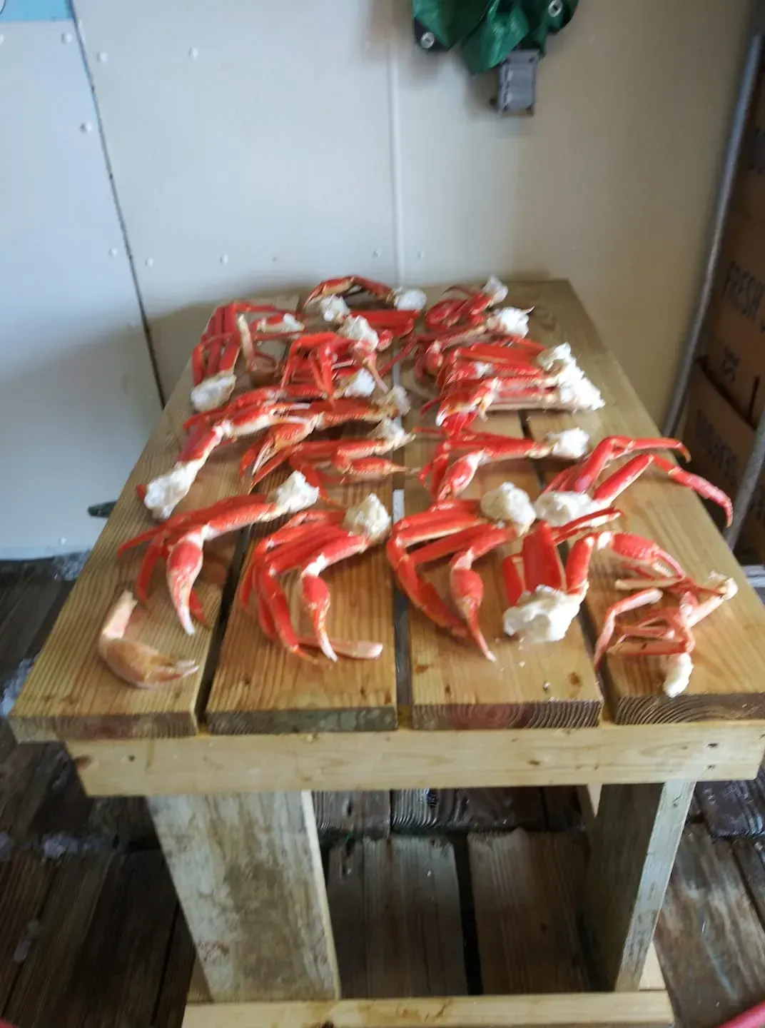 Cooked red crab legs on a wooden table, possibly a seafood processing area.