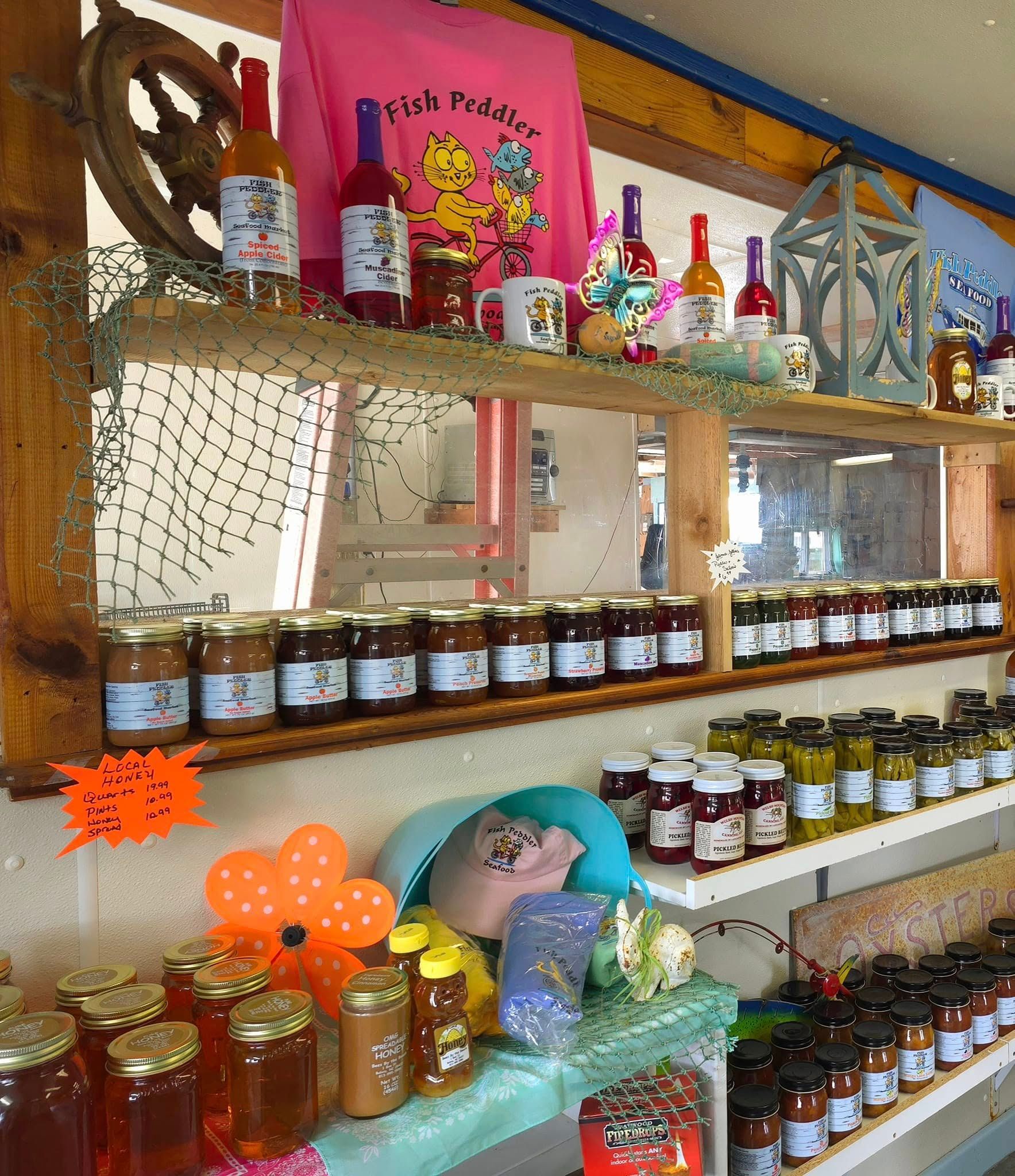 Shelves stocked with jars of preserves, bottles, and a t-shirt; a retail display.