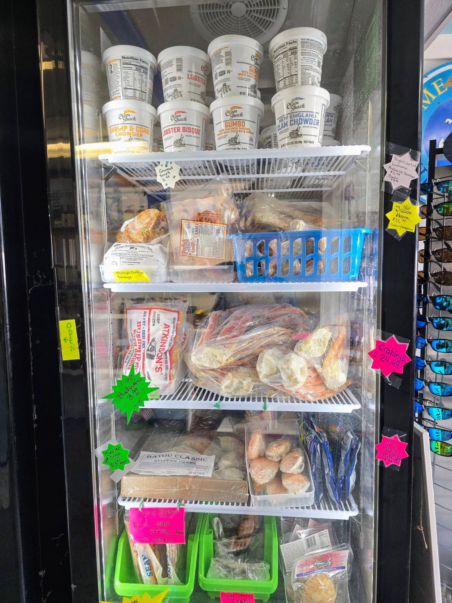 Glass-fronted refrigerator filled with various food products, including containers, packaged items, and baskets.