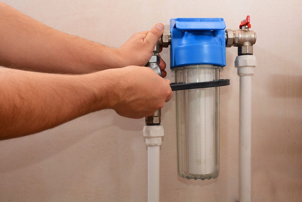 A Person is Installing a Water Filter on a Pipe — Brett Negus Plumbing In Hervey Bay, QLD