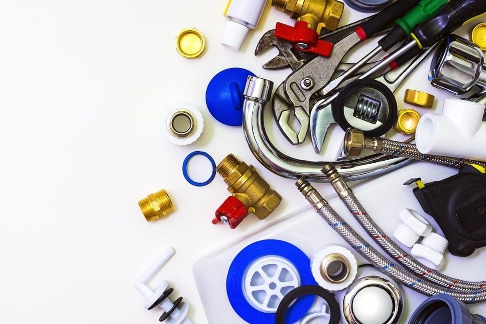 A Bunch of Plumbing Parts and Tools on a White Surface — Brett Negus Plumbing In Maryborough, QLD