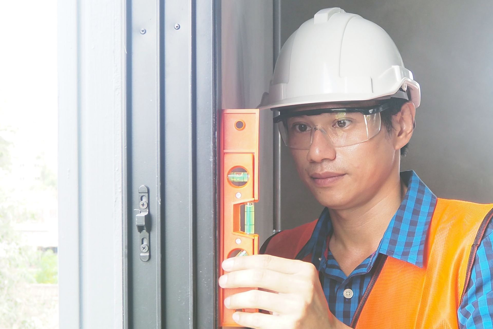 A construction worker is using a level to check the level of a door.