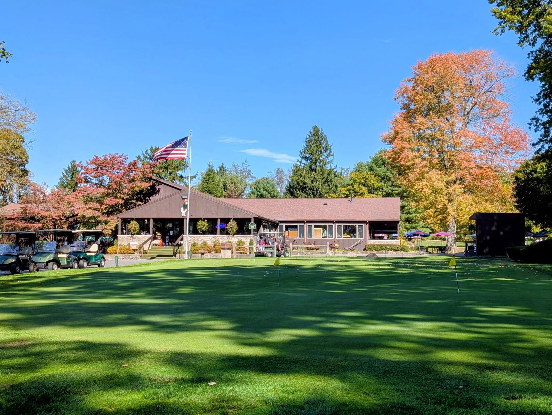 Golf course clubhouse with an American flag and fall foliage.