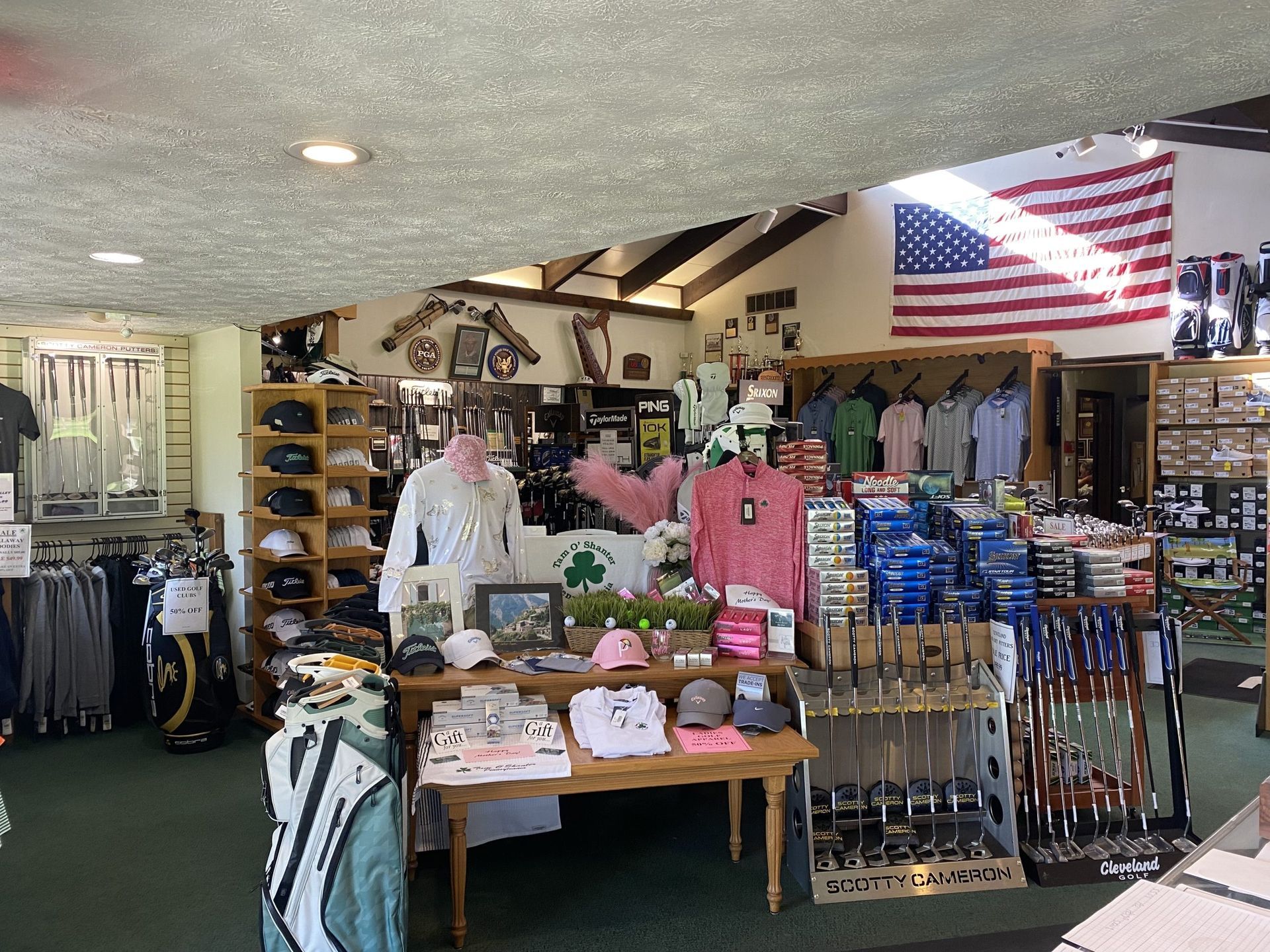 Golf shop interior with merchandise displays, an American flag, and a mannequin.