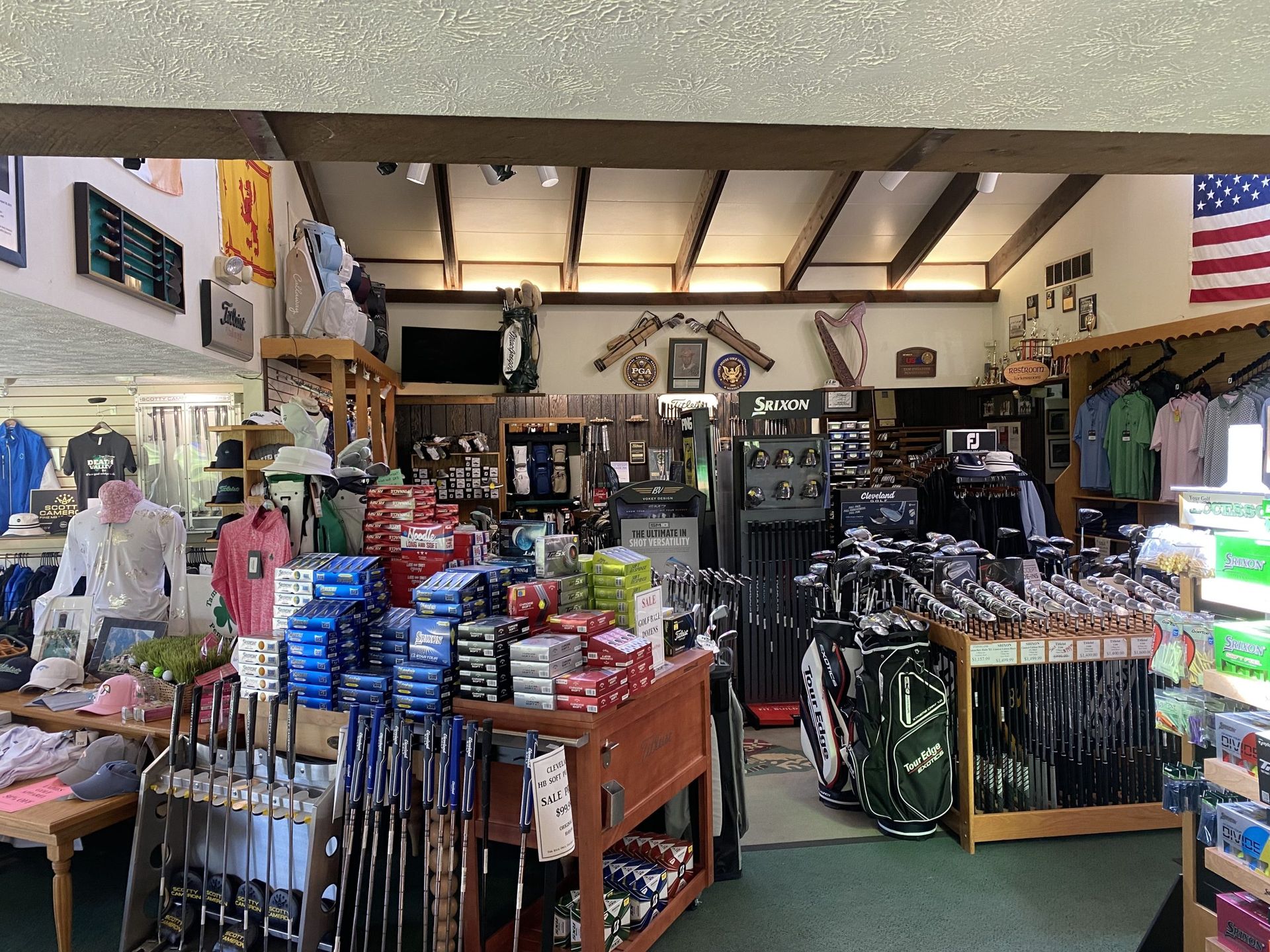 Golf shop interior with clubs, apparel, and accessories on display.