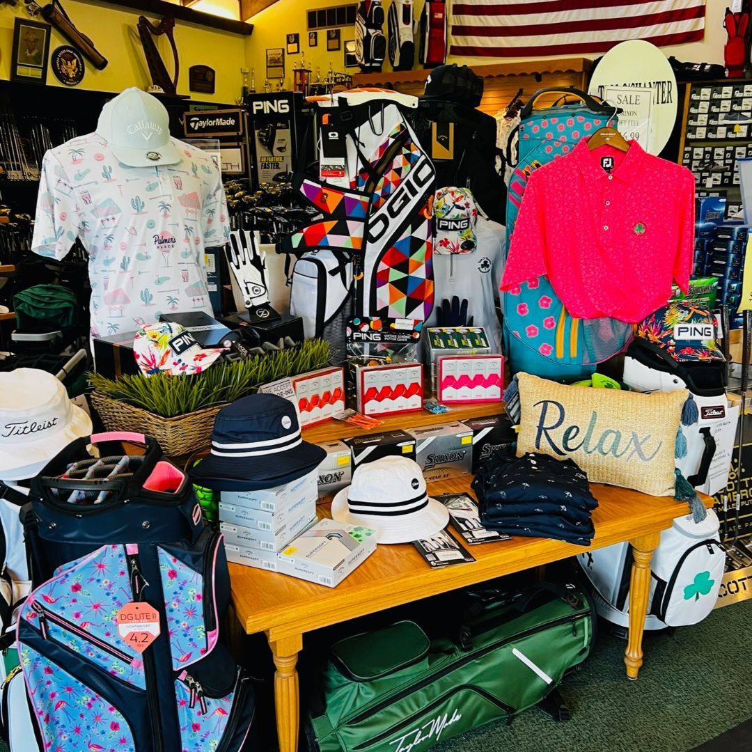 Golf shop display with shirts, hats, bags, and accessories in various colors.