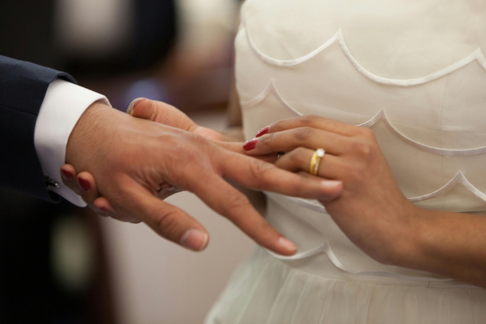 Bride placing a gold ring on groom's finger during a wedding ceremony.