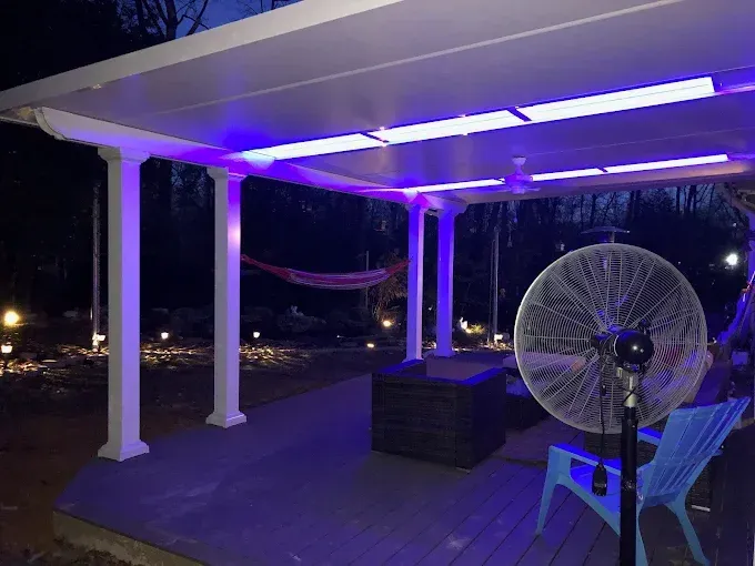 A patio with purple LED lighting, a fan, and a hammock at night.