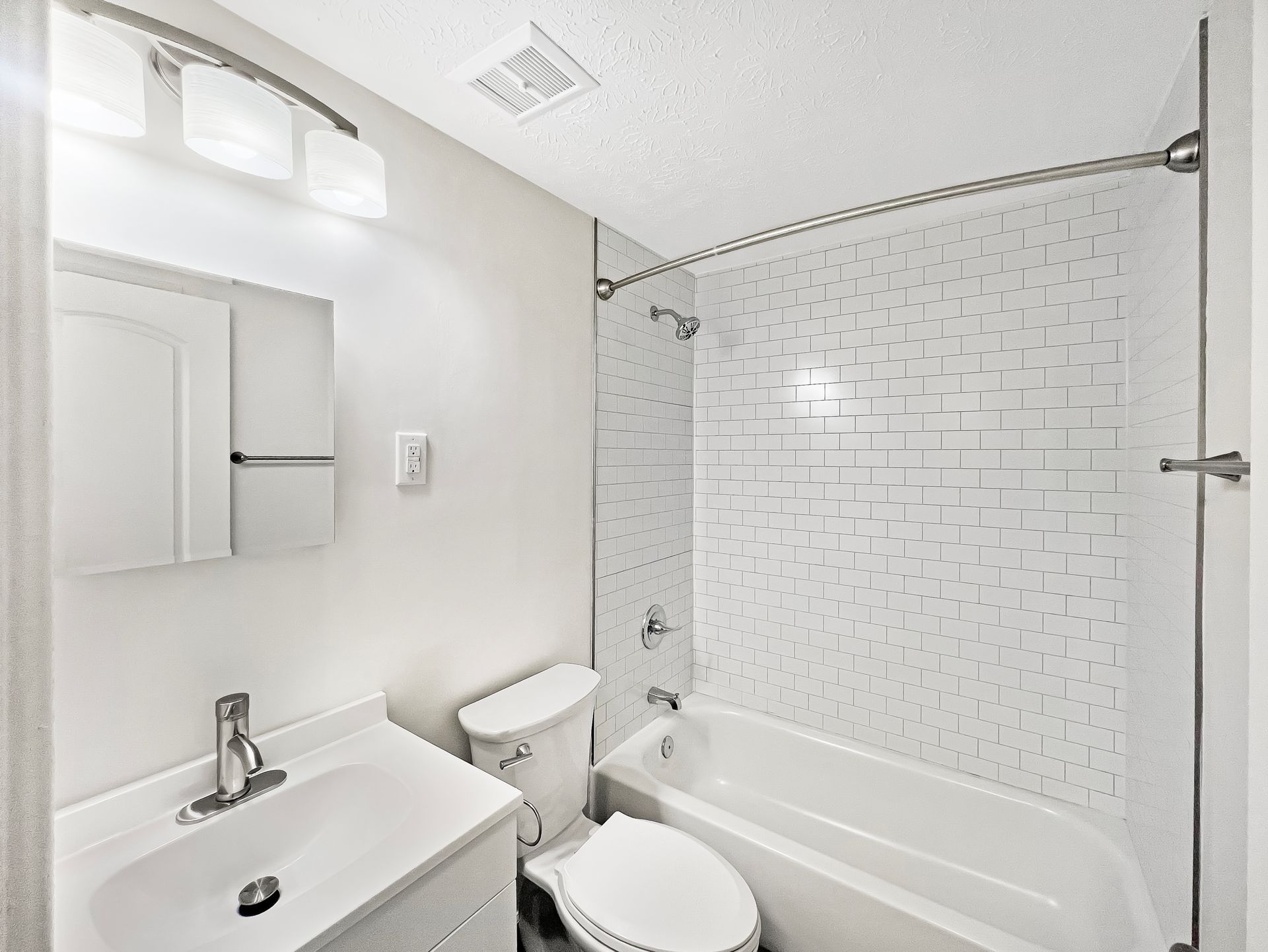 White bathroom with vanity, toilet, and bathtub/shower combo.