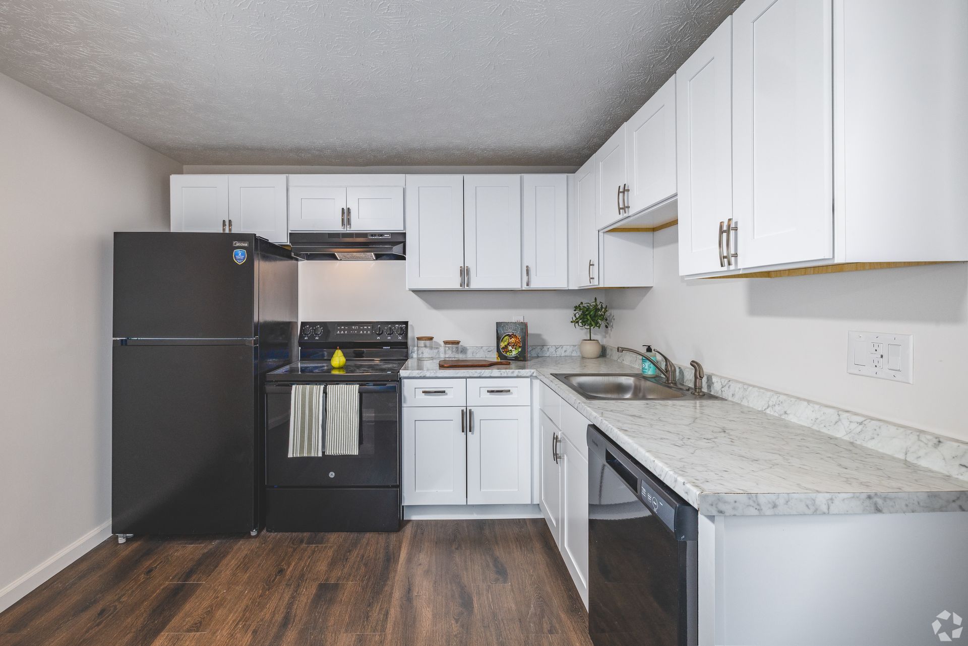 Updated kitchen at Overlook at Sunset with white cabinets, black appliances, and granite-style countertops.
