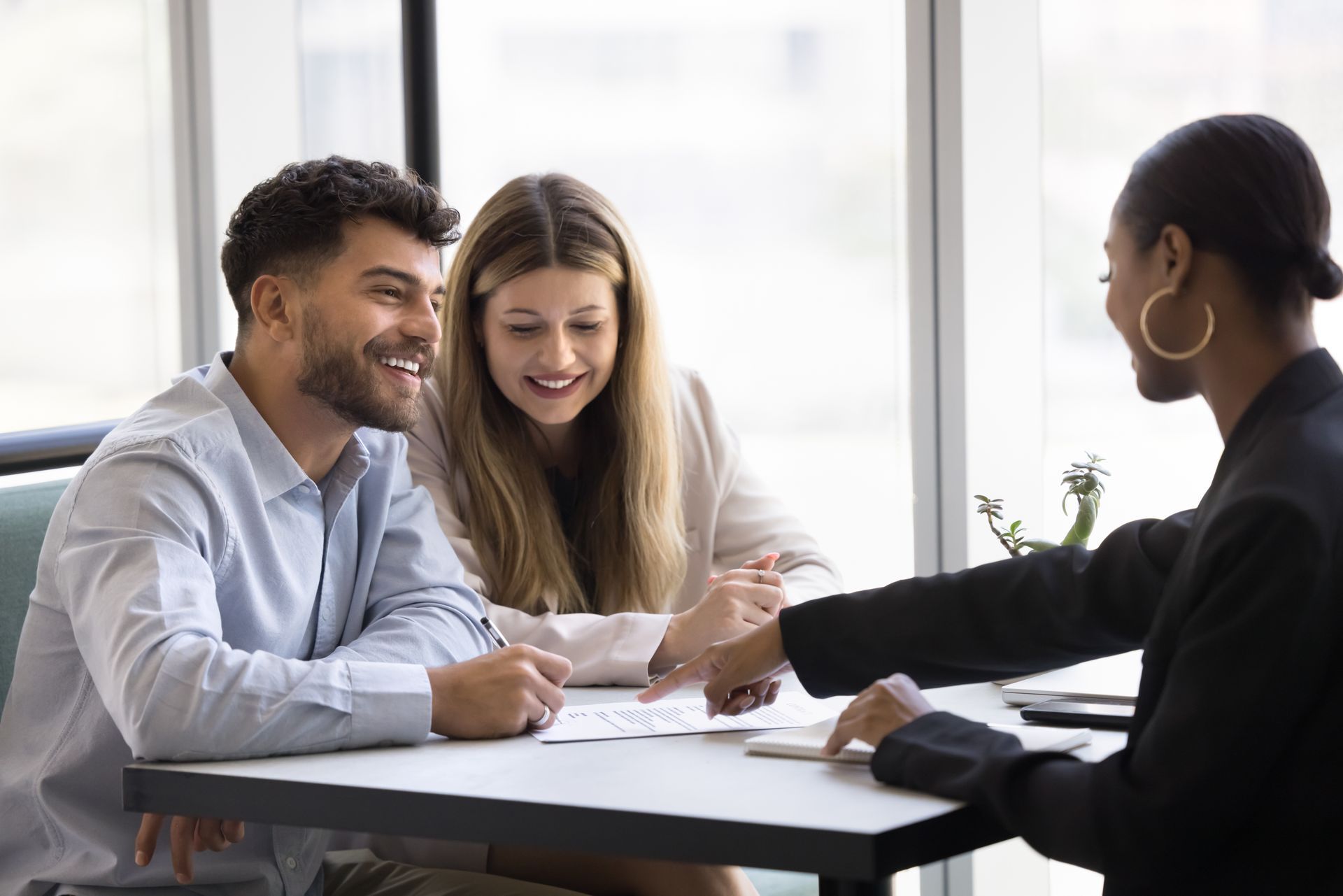 A lawyer meeting with a couple at a desk to review and discuss documents. A lawyer meeting with a couple at a desk to review and discuss documents.