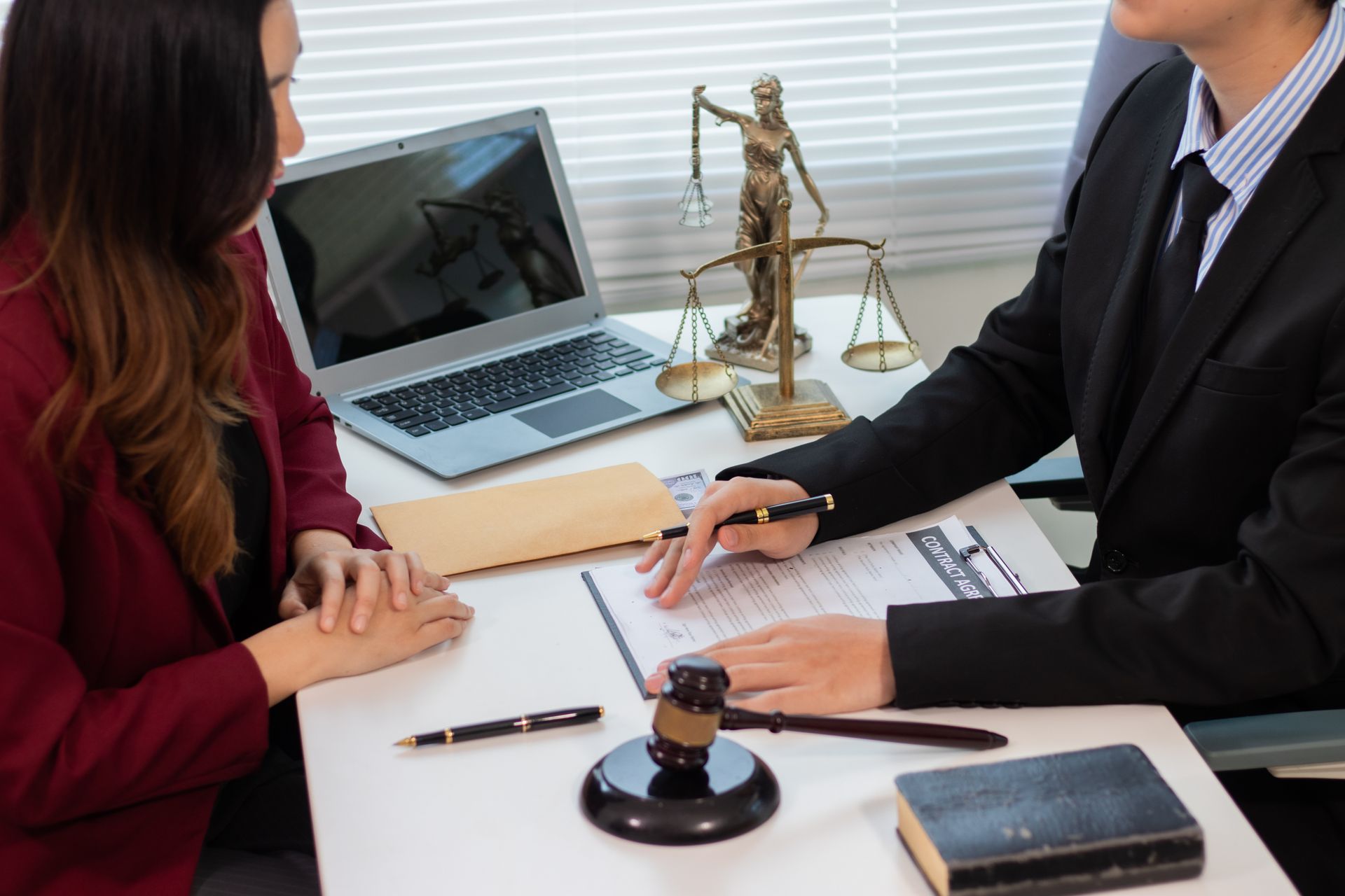 A legal consultation showing a lawyer and client seated at a desk with legal documents. A legal consultation showing a lawyer and client seated at a desk with legal documents.