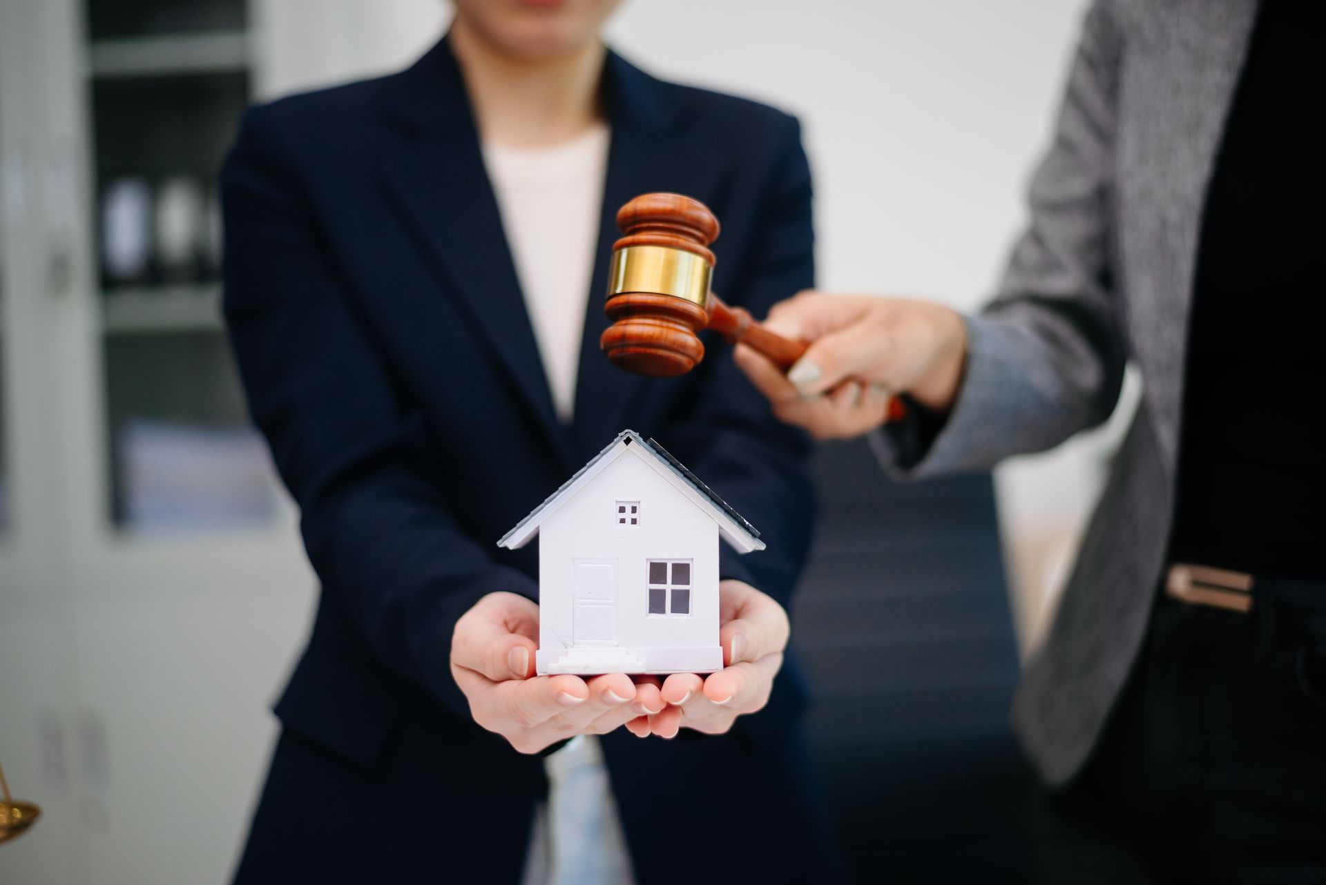 Judge gavel striking next to house model. Judge gavel striking next to house model.