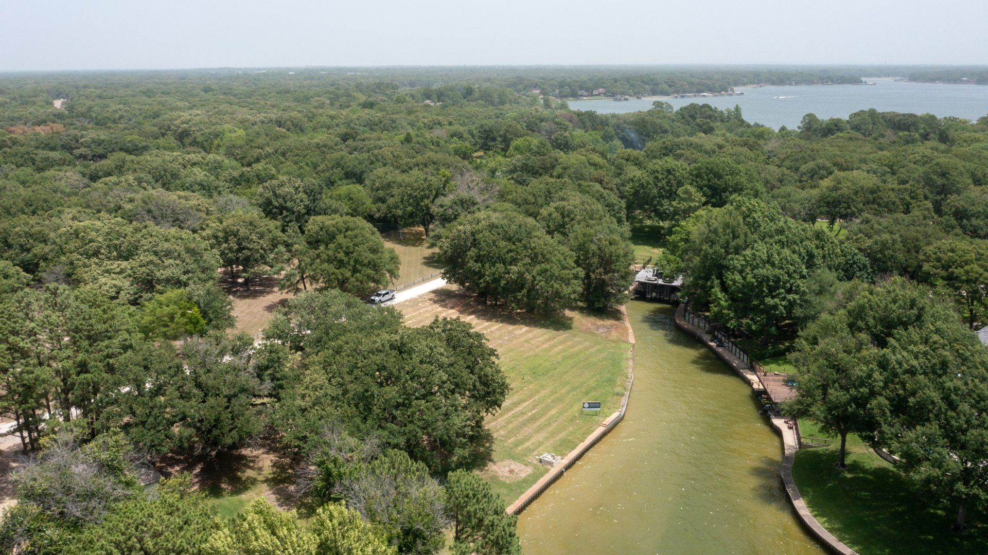 An aerial view of a park with trees and a lake in the background