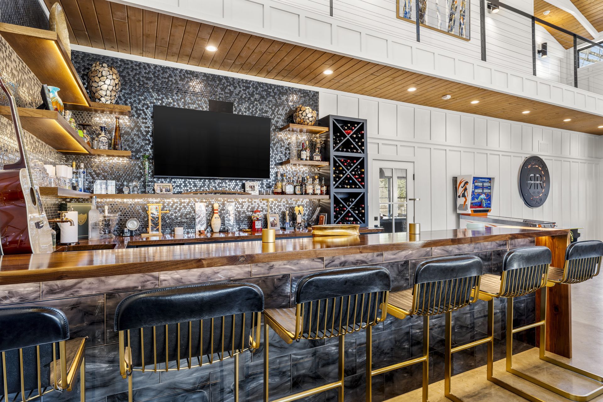 A bar with stools and a television on the wall.