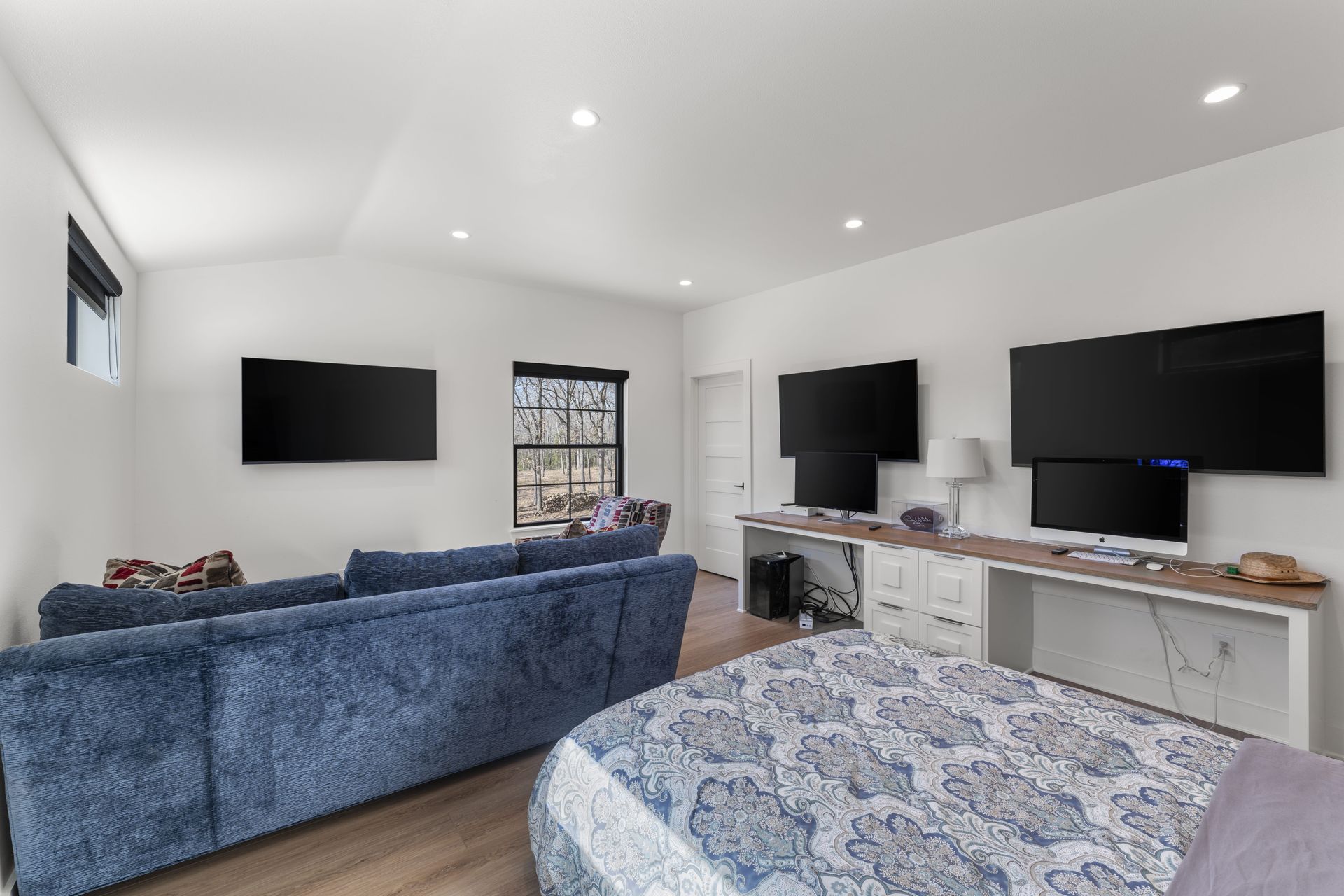 A living room with a blue couch and two flat screen tvs