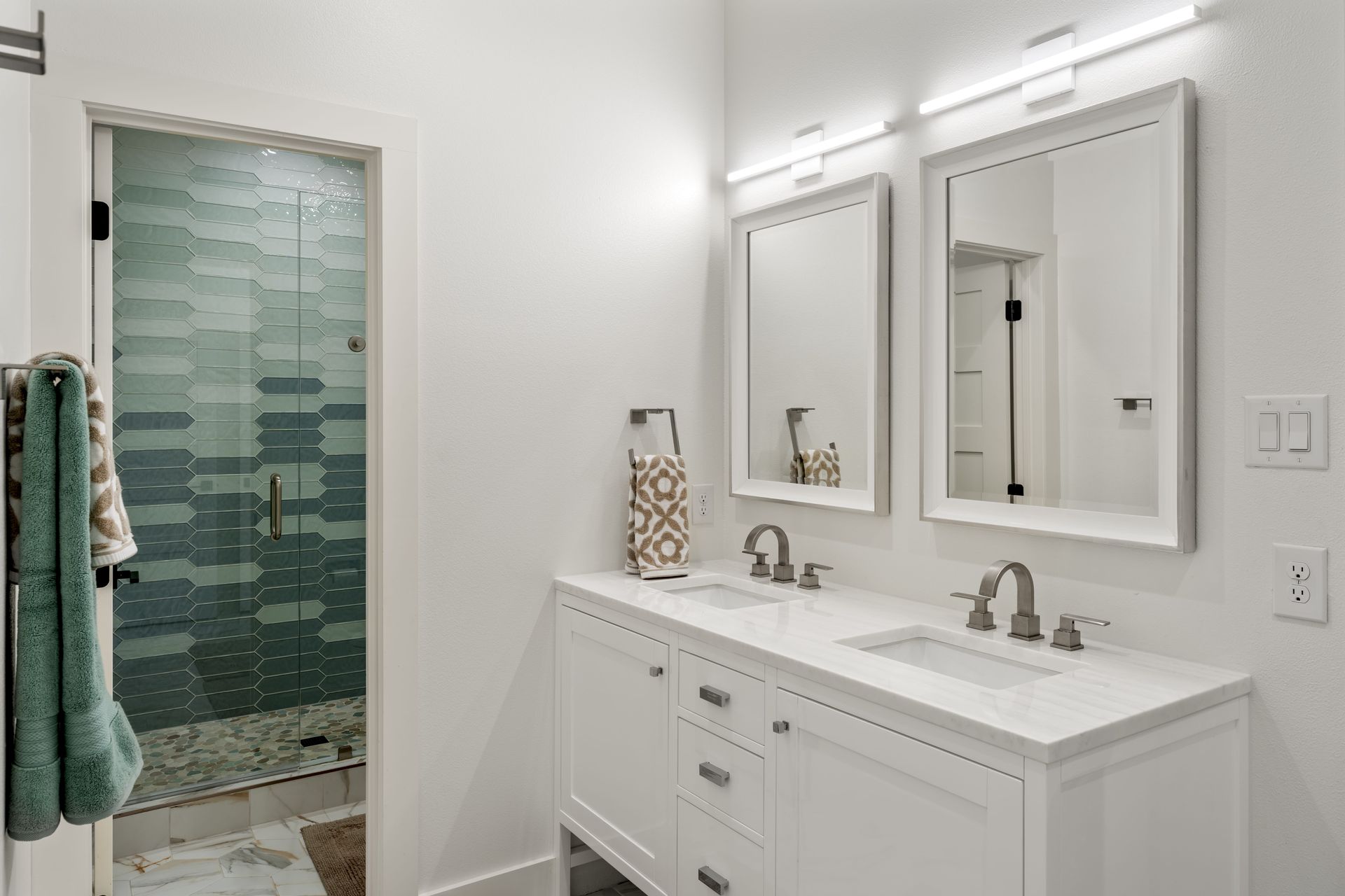 A bathroom with two sinks , two mirrors and a walk in shower.