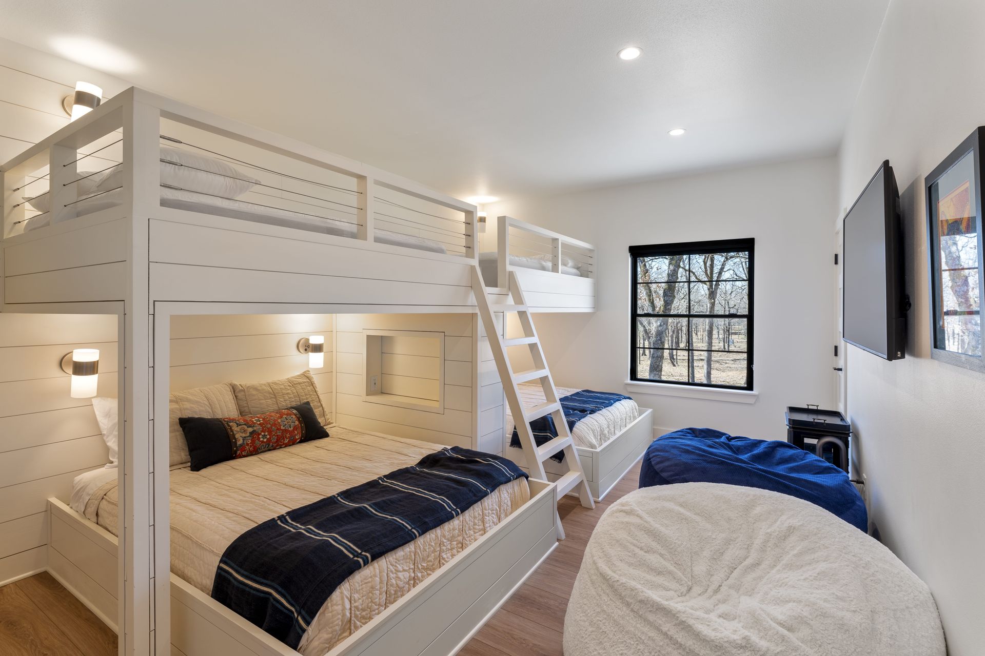 A bedroom with three bunk beds and a television.