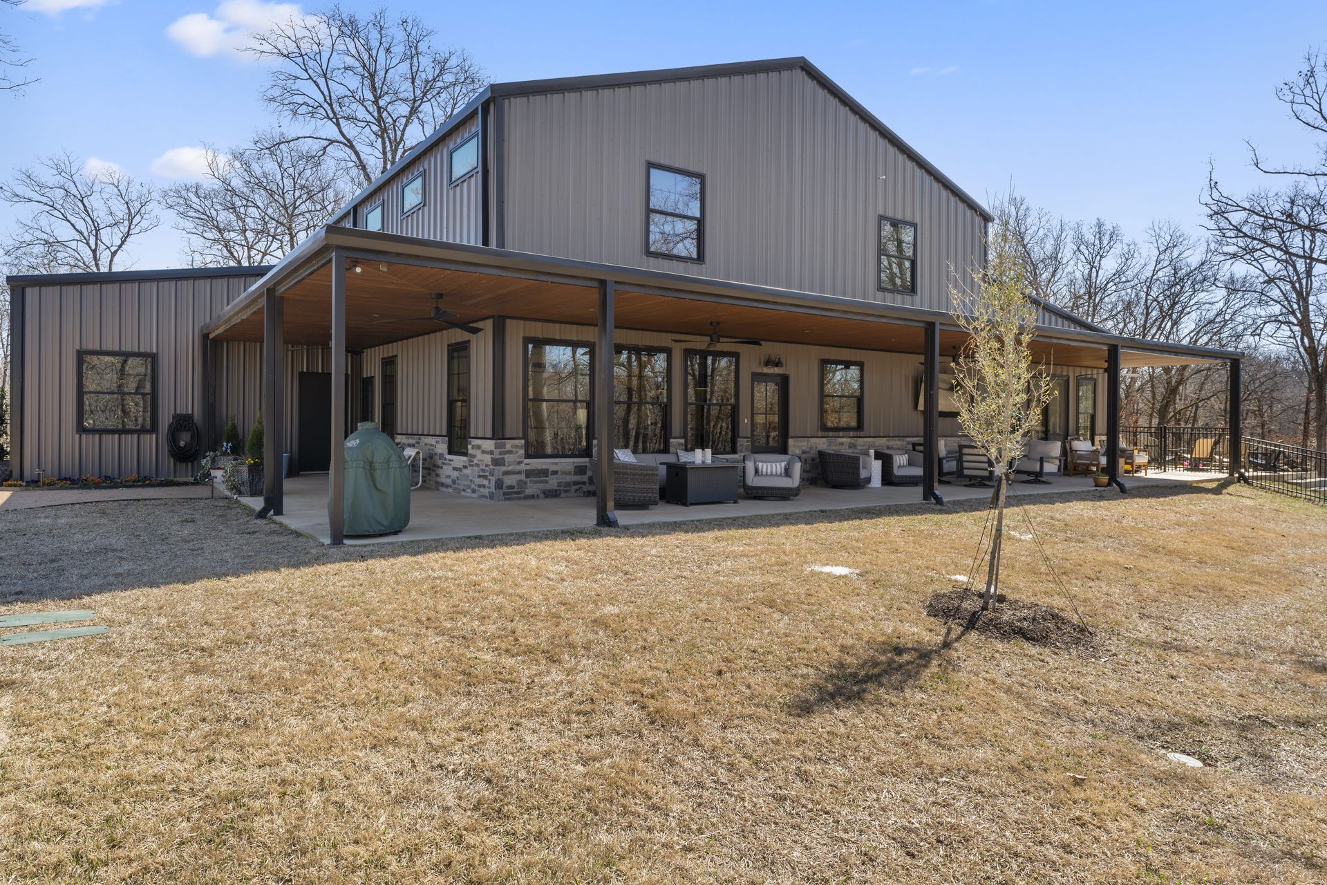 A large house with a porch and a tree in front of it.
