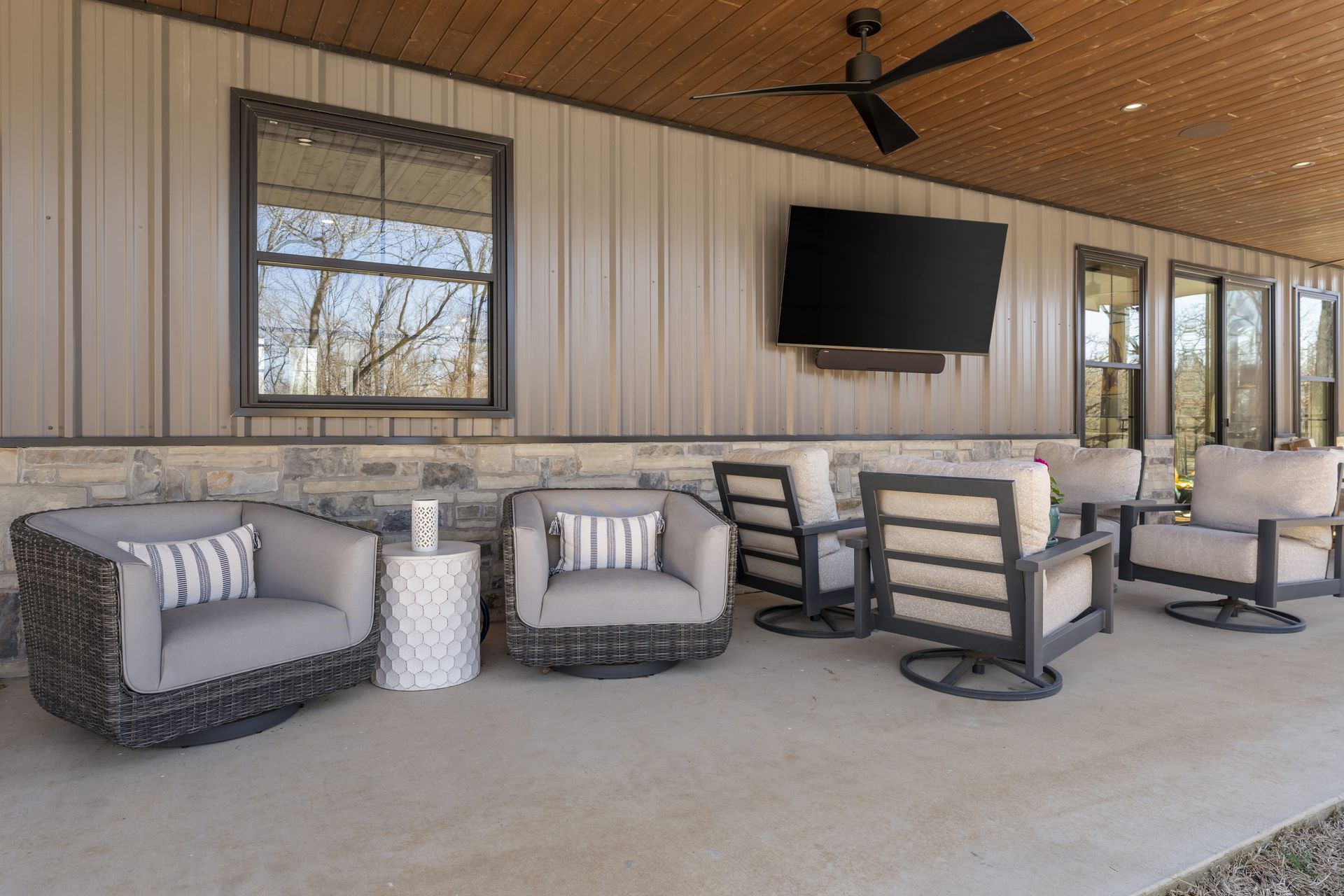 A patio with chairs , tables and a television on the wall.