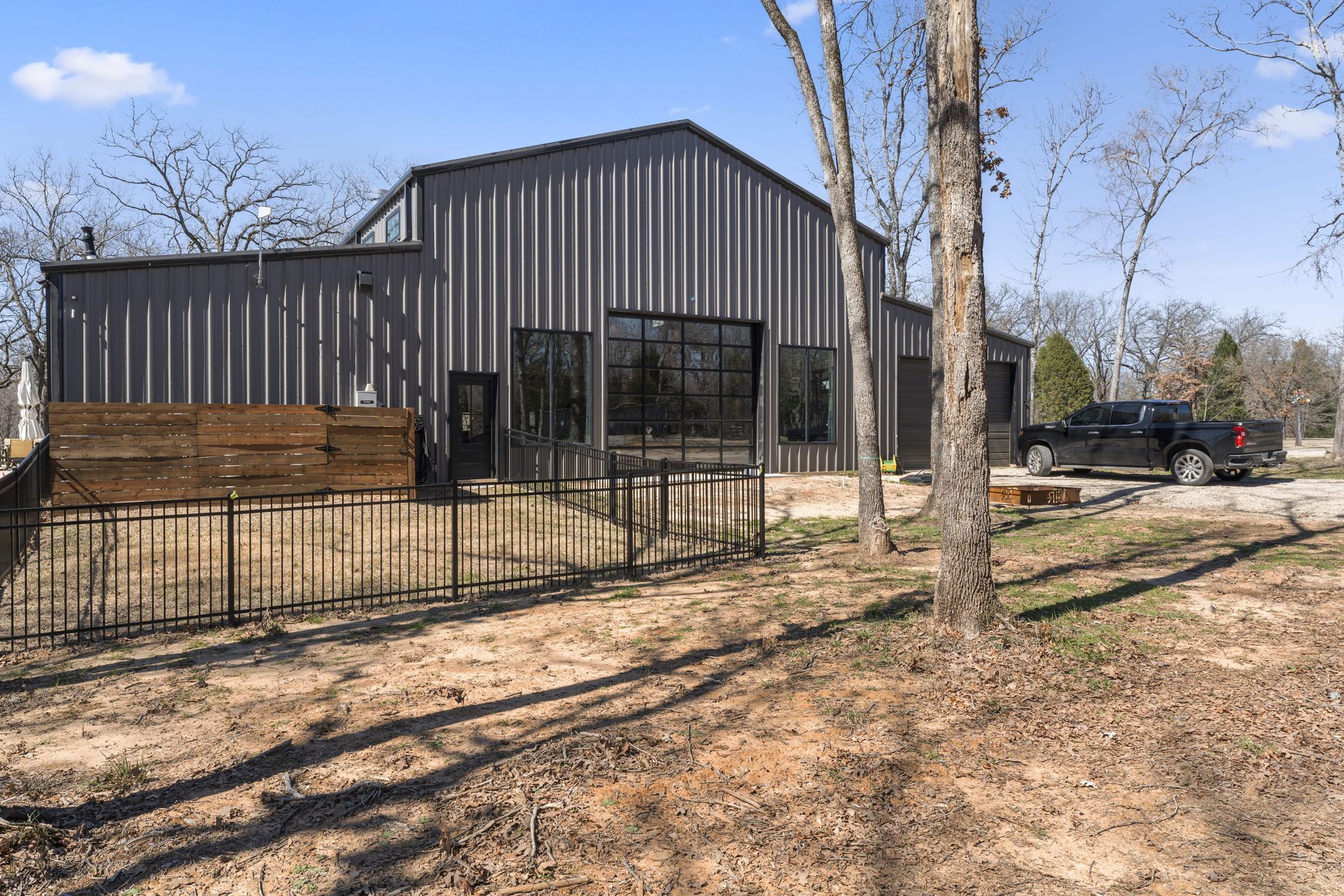 A black truck is parked in front of a large metal building.