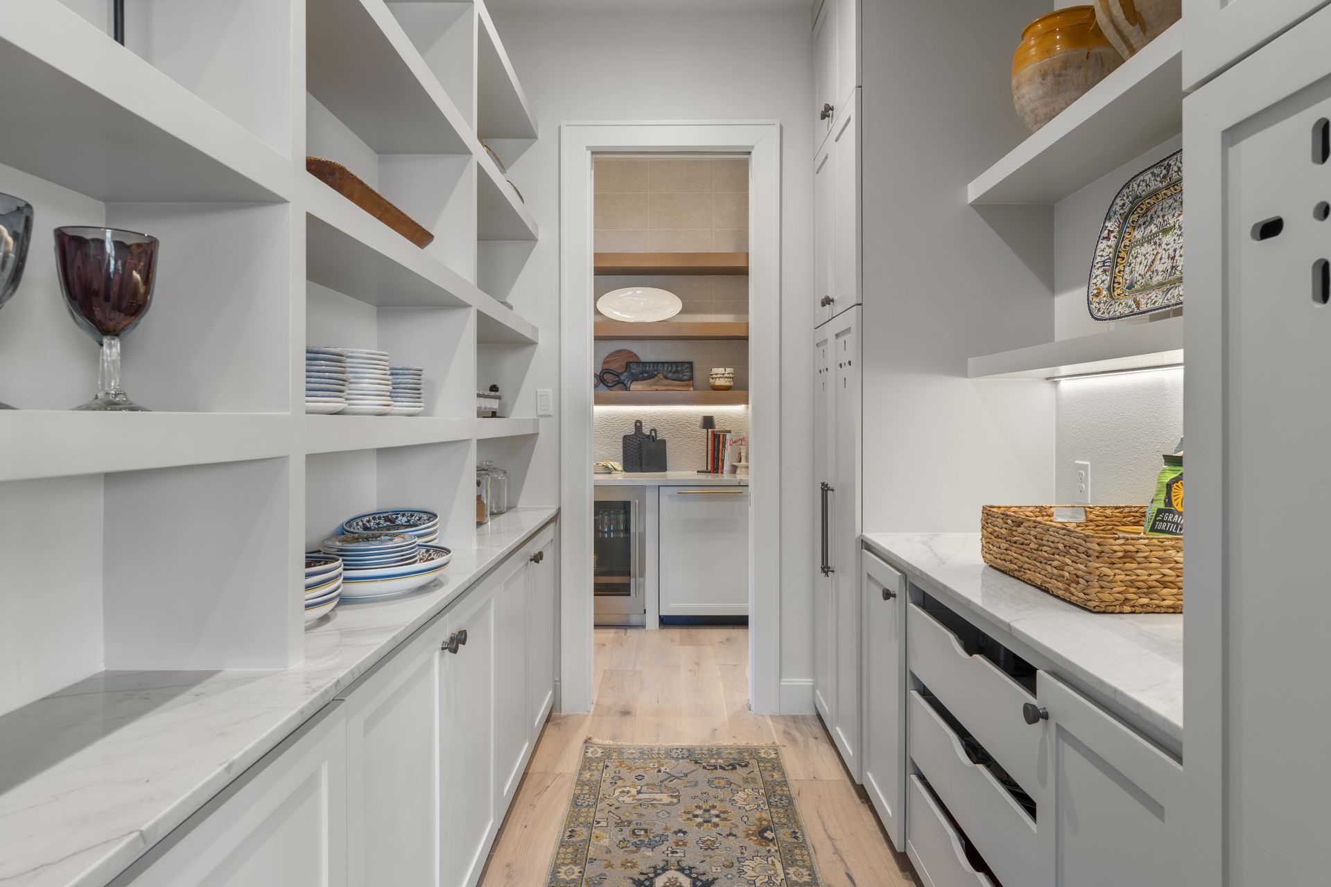 A pantry with lots of shelves and drawers and a door leading to a kitchen.