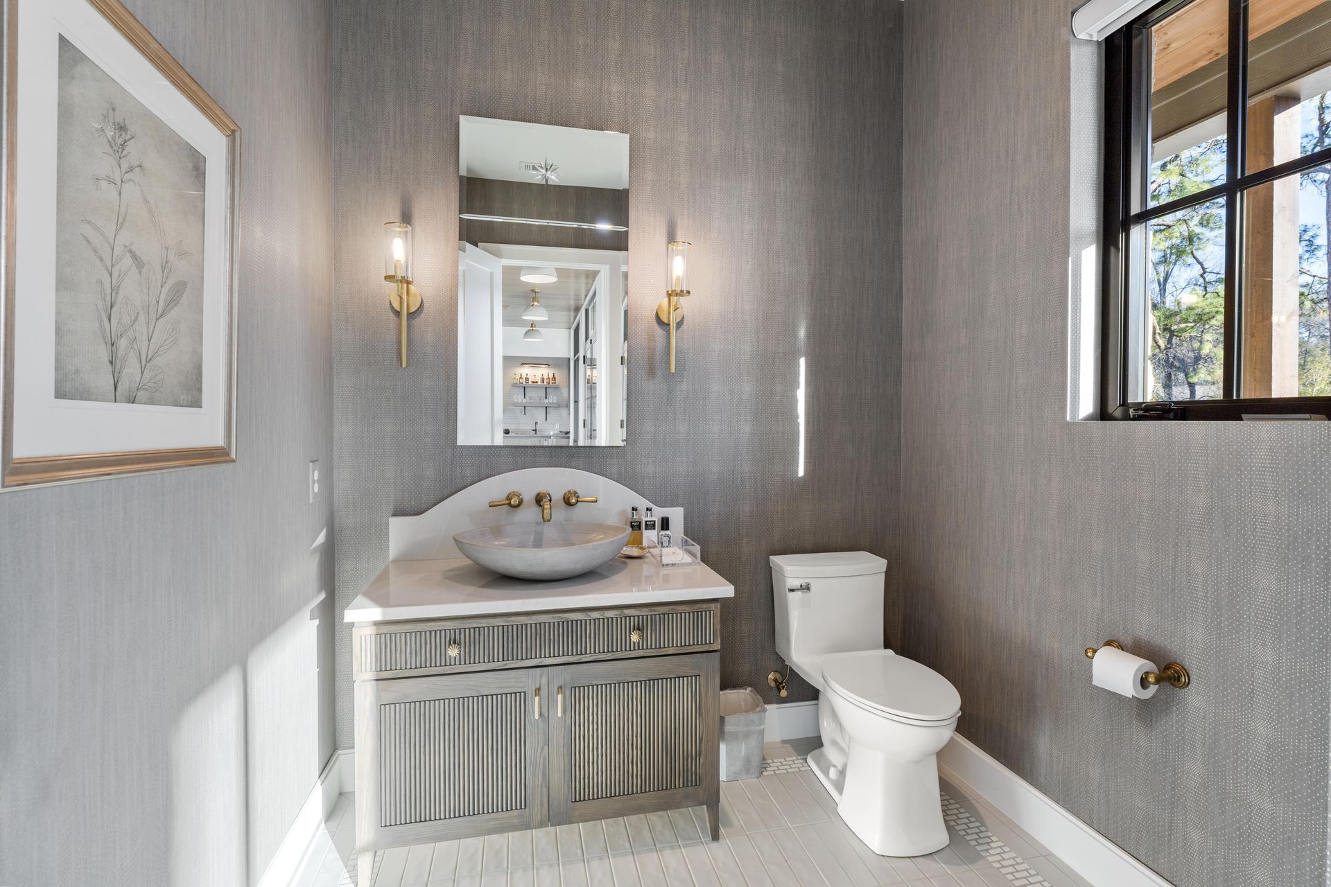 A bathroom with a sink , toilet , mirror and window.