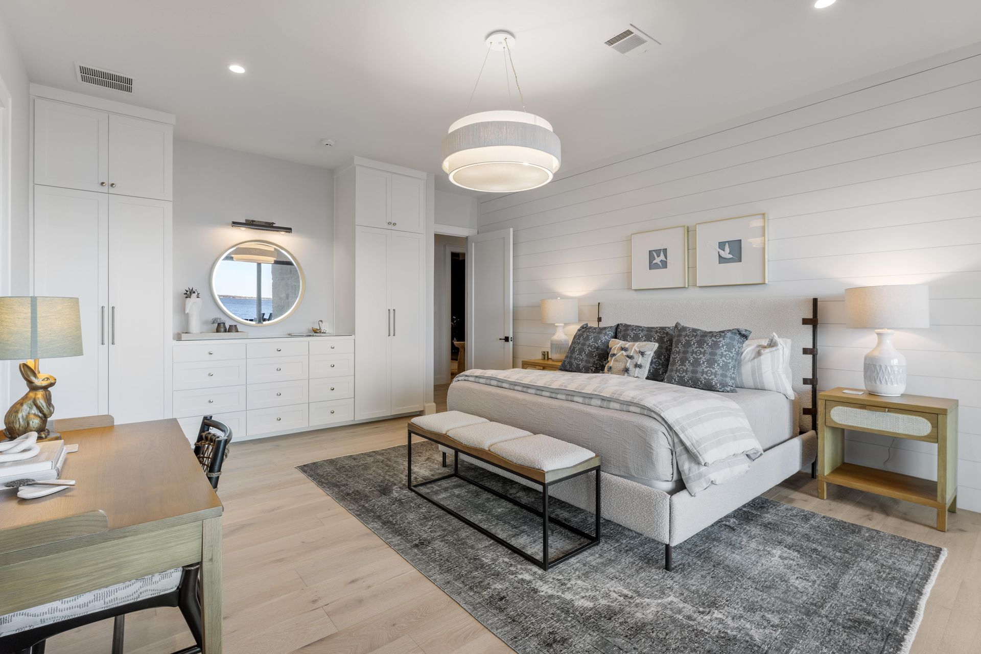 A bedroom with a king size bed , desk , nightstand , dresser and mirror.